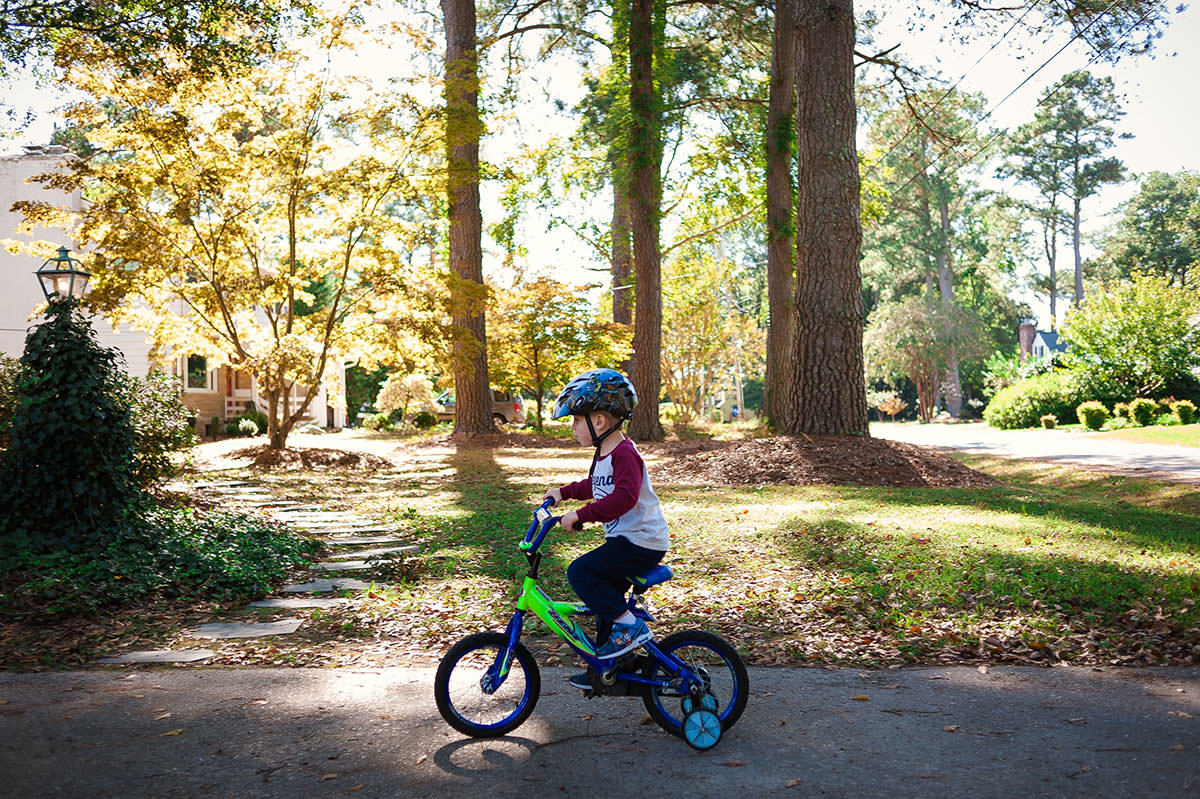 boy riding bike with training wheels