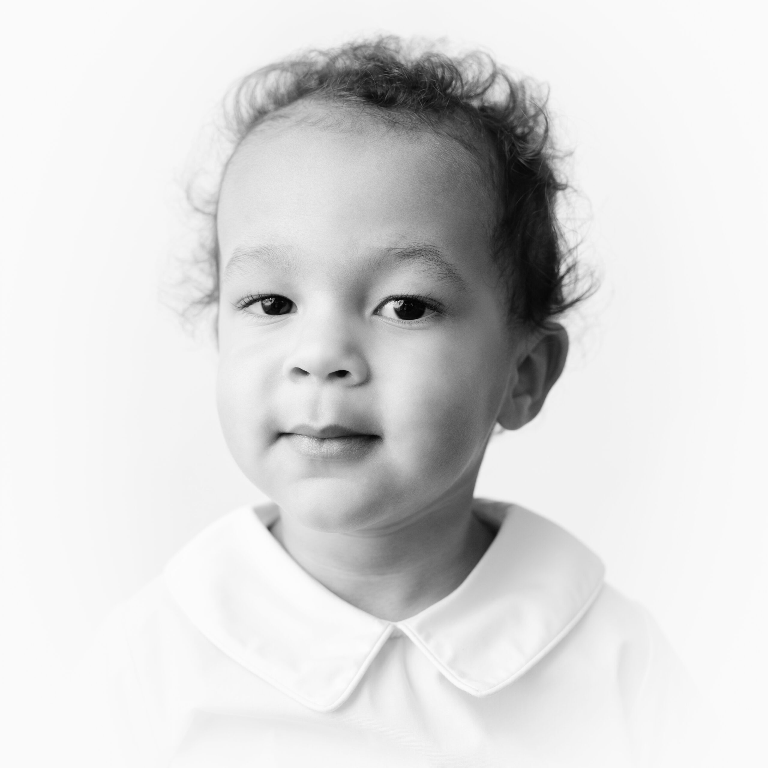 Black and white heirloom portrait of young boy smiling at camera.