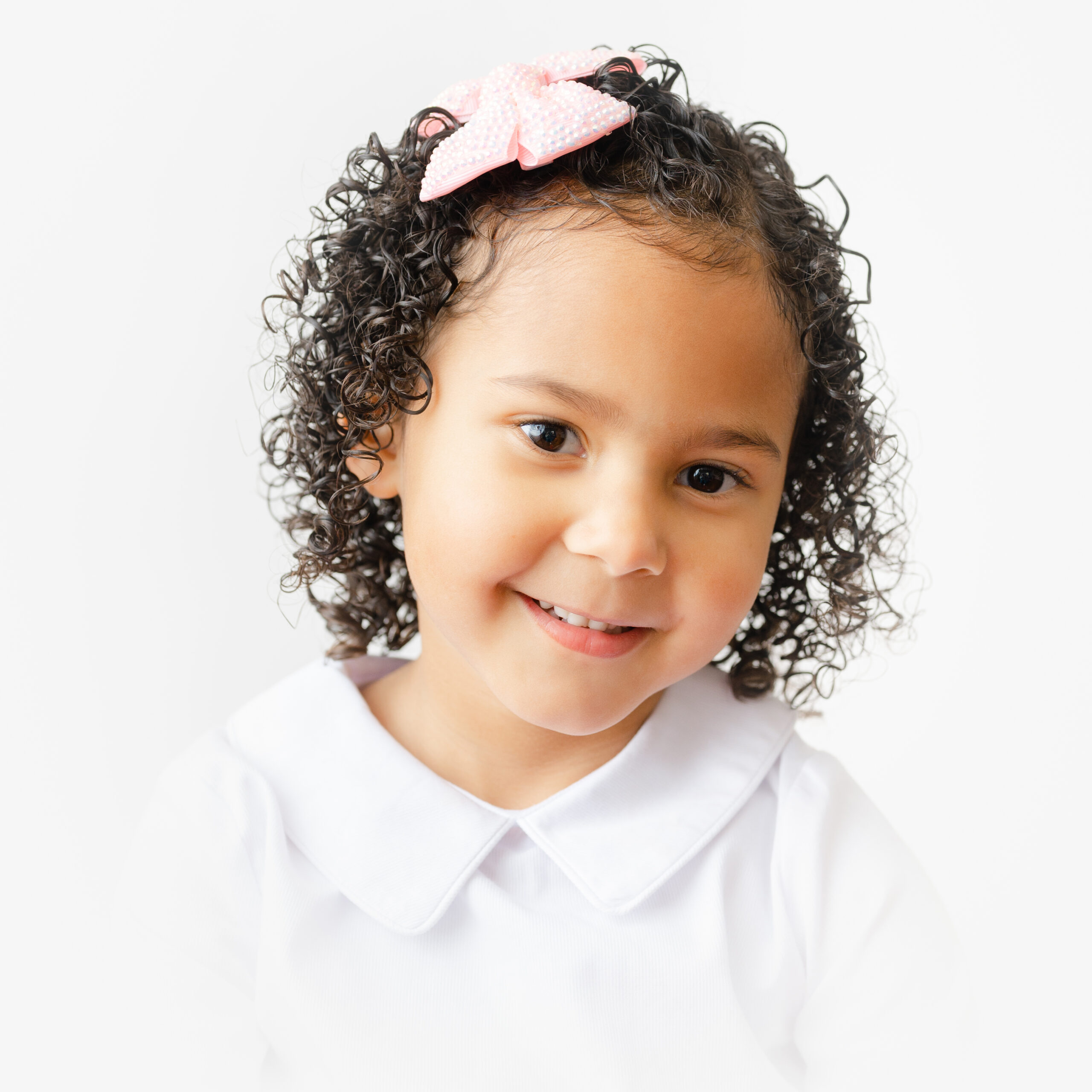 Little girl with beautiful curls smiles during her photo session.