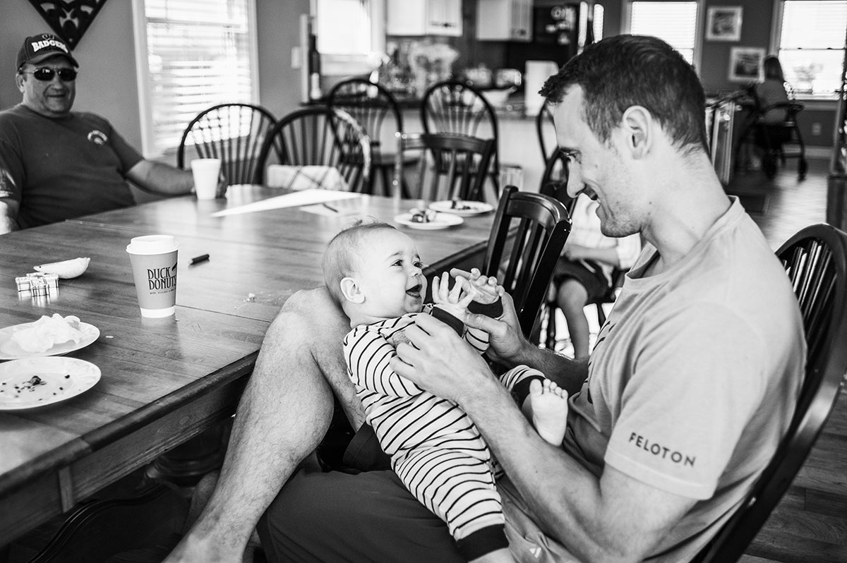 Father smiles at baby in lap during outer banks, nc family session.