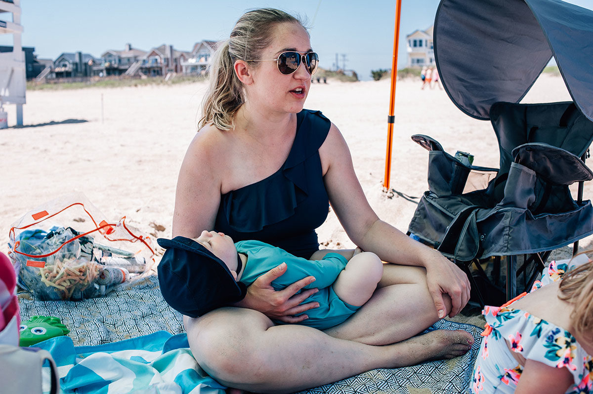 Mother chats while baby sleeps in her arms in Outer Banks captured by Dreama Spence.