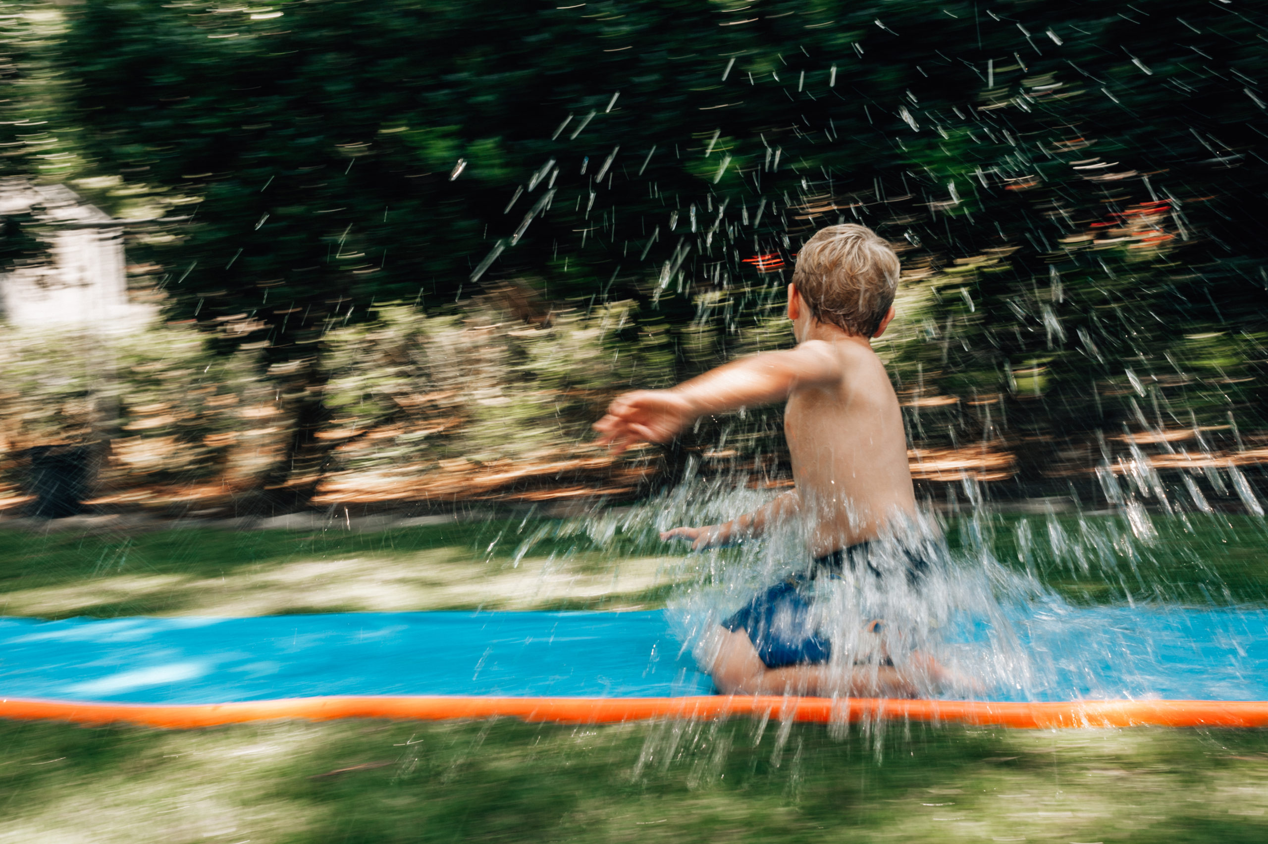Boy enjoys slip in slide during williamsburg family session.