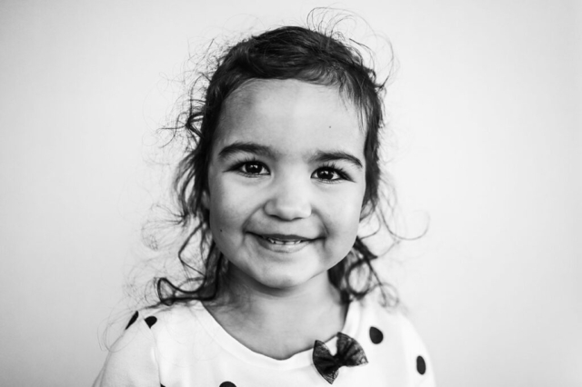 Black and white preschool portrait of girl with polka dot shirt.