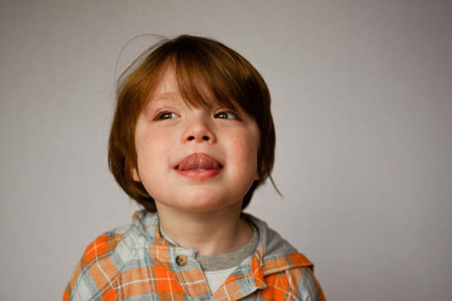 Little boy sticks his tongue out during school portraits.