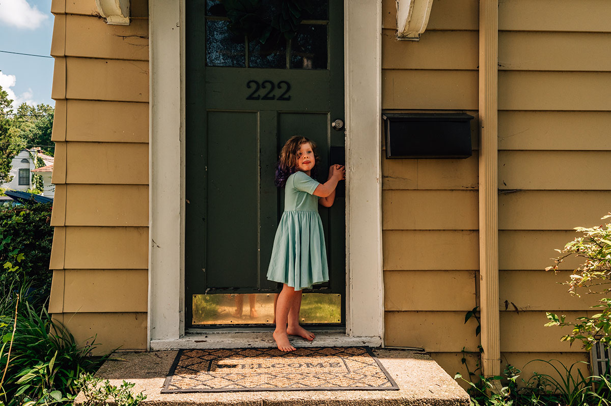 Little Ophelia stands at the front of her door wearing a beautiful aqua a-line dress.