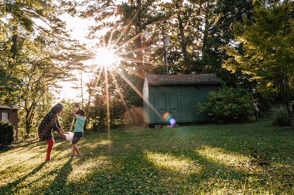 On a summer afternoon a grandmother helps her grandson get on to a zip line