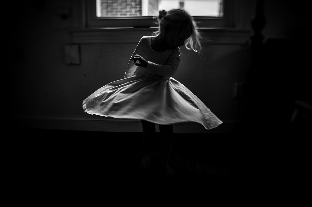 black and white photo of a girl twirling in a dress