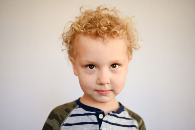 Little boy gives a sweet, shy look during preschool portraits.