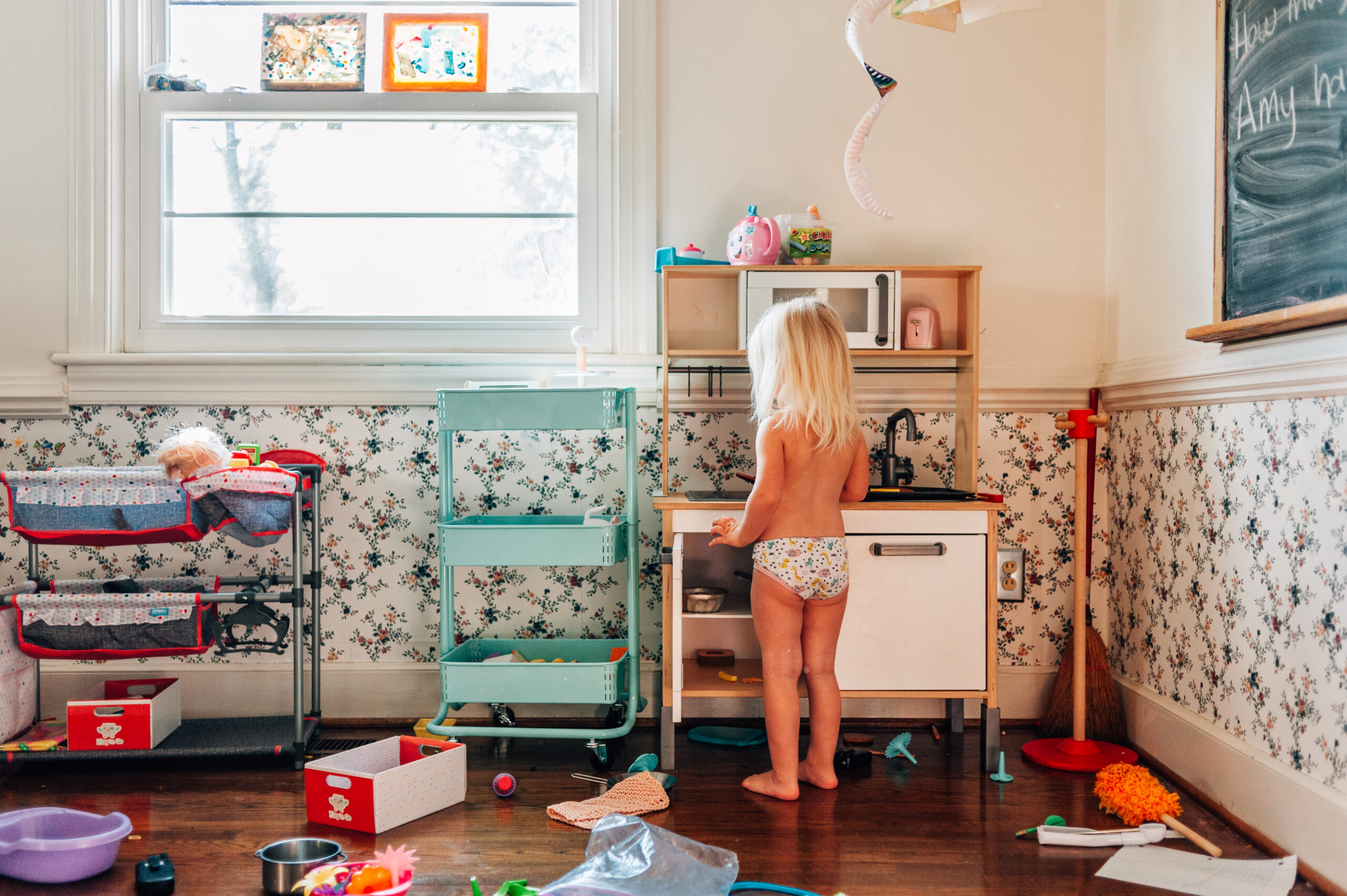 Little girl plays with toy kitchen during in-home family session with Dreama Spence.