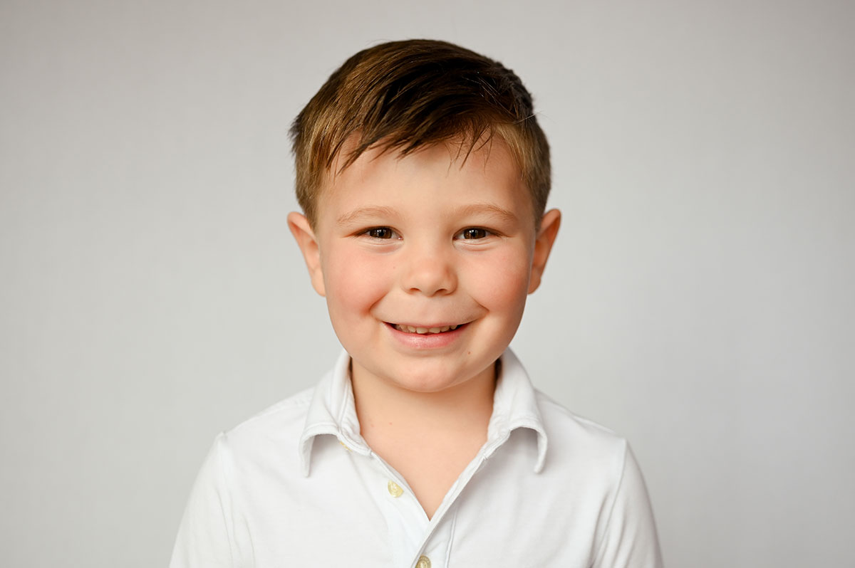 Boy wears white polo for Virginia Beach preschool portraits.