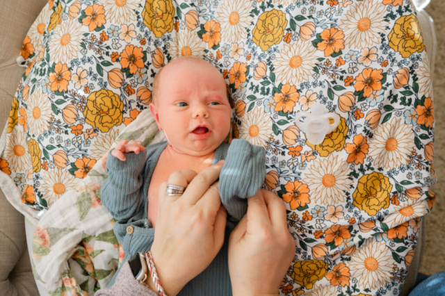 Mother dresses newborn during in-home newborn lifestyle photo session.