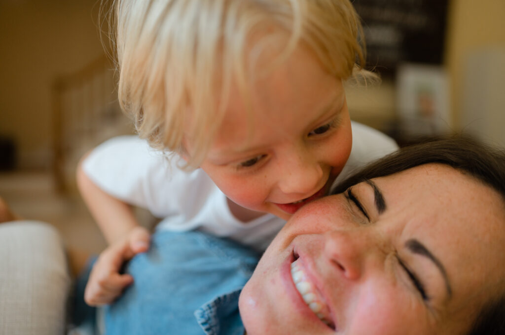 Mom laughs as son gives her butterfly and Eskimo kisses on the cheek.