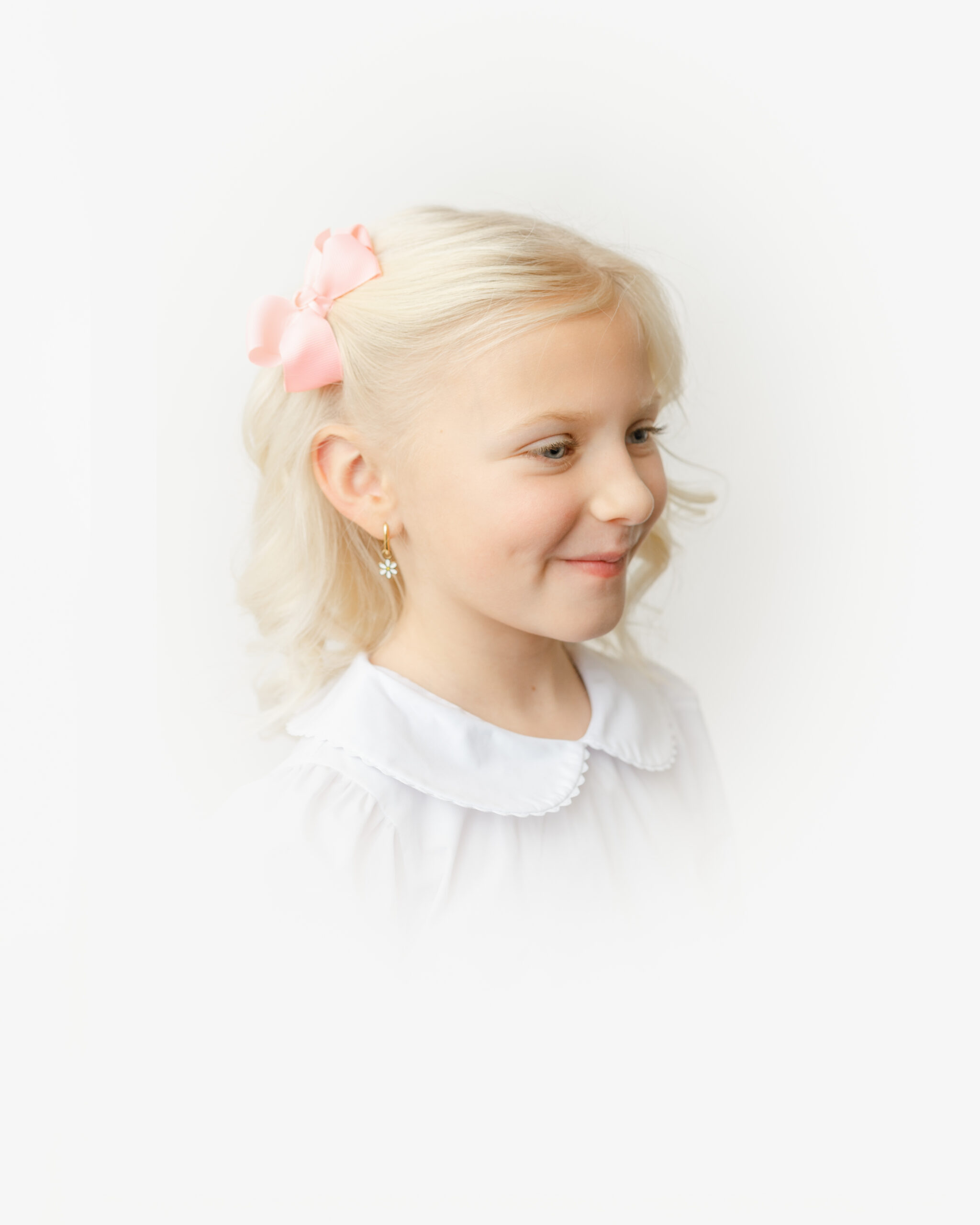 Little girl with bow looks off to the right during her heirloom vignette portrait.