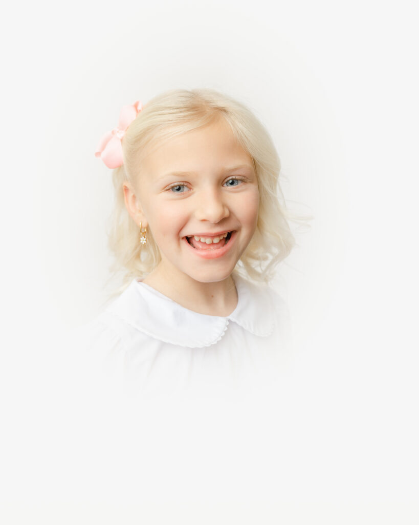 Blonde haired girl wears pink bow for her Heirloom portrait.