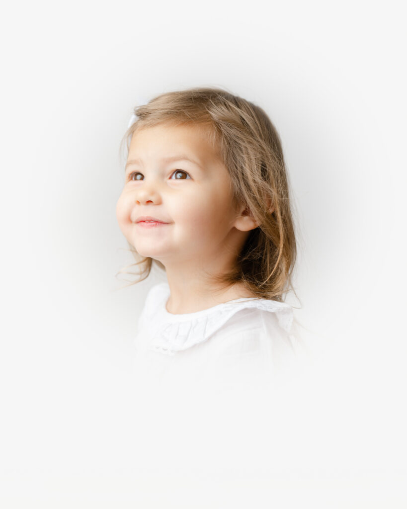 Photography portrait of a 2 year old in front of a white backdrop.