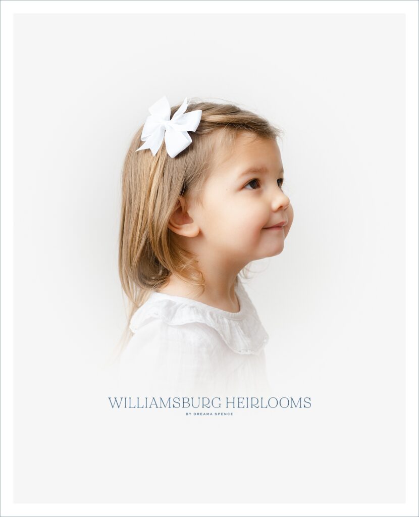 Little girl wears a classic white bow in her hair during heirloom portrait event.
