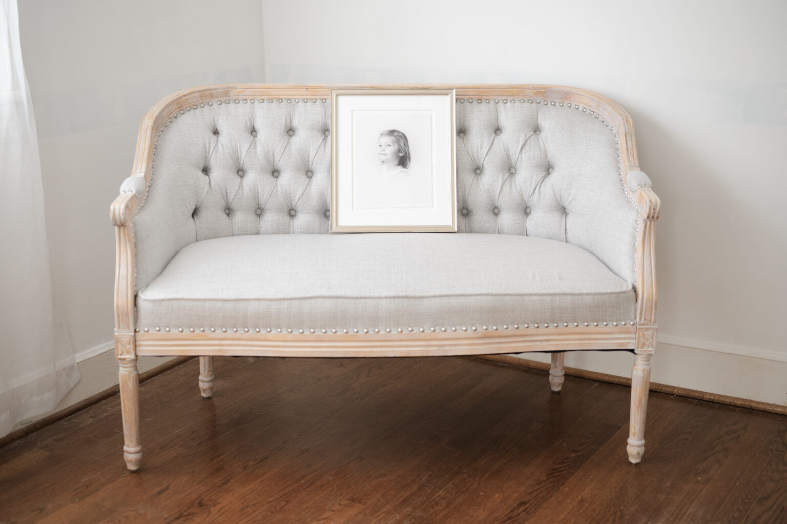 A framed heirloom vignette is displayed on a tufted sette.