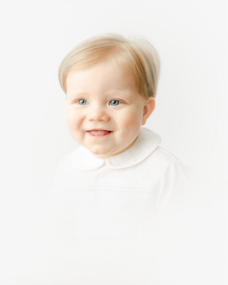 A little boy wearing a Peter pan collar smiles for his heirloom vignette photography session.