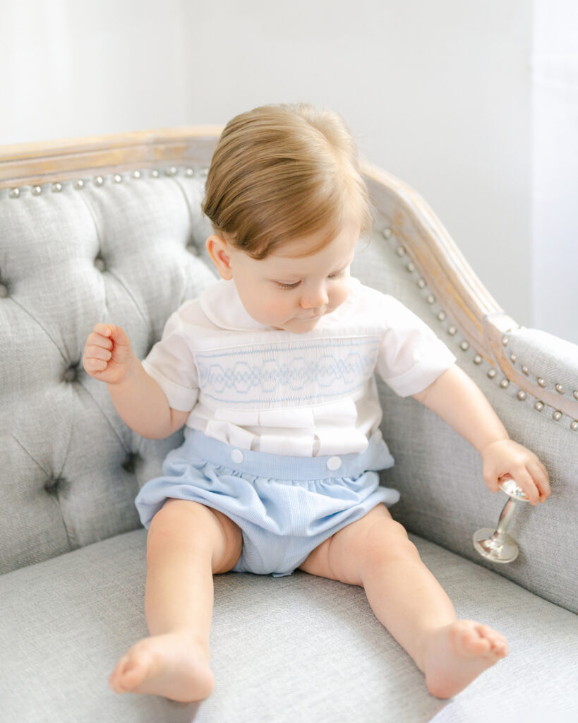 Little boy dressed in blue and white outfit and holds a silber rattle during a lifestyle session with Williamsburg Virginia Photographer, Dreama Spence