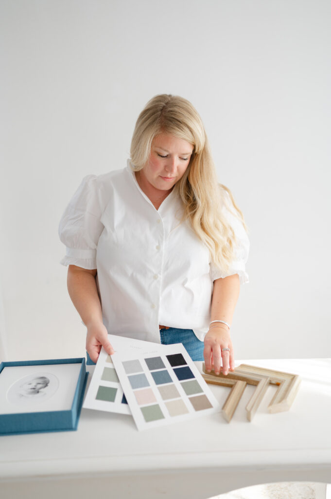 Dreama holds album swatches and frame options for photography client.