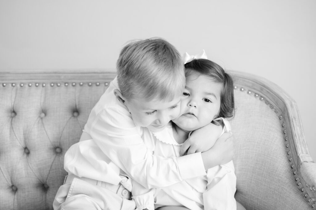 Big brother squishes little sisters face with a hug.