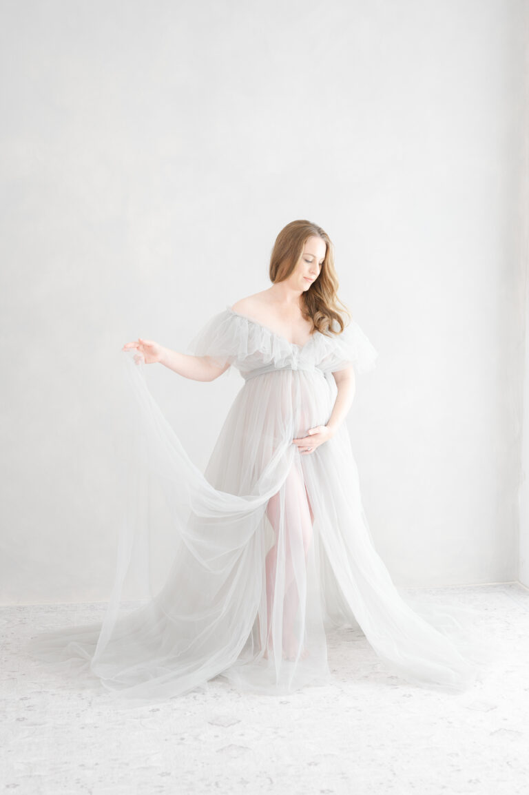 Mom holds plays with her dress during her vrginia beach maternity photography session.