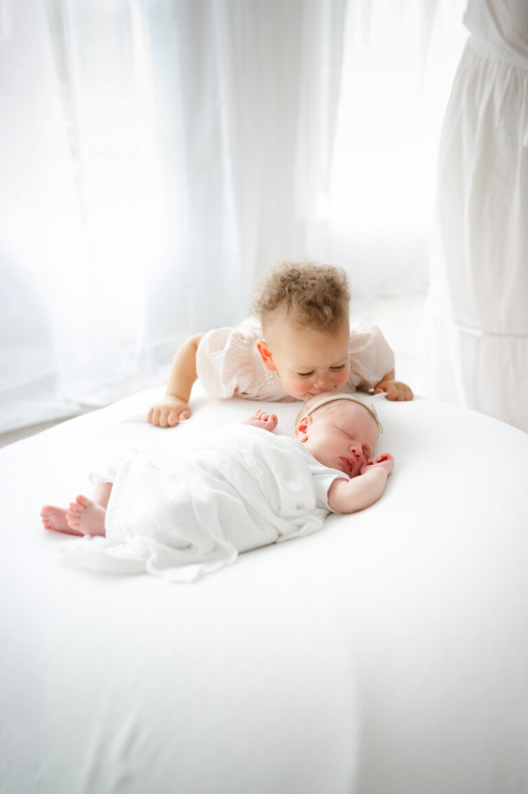 Big sister kisses newborn sister.