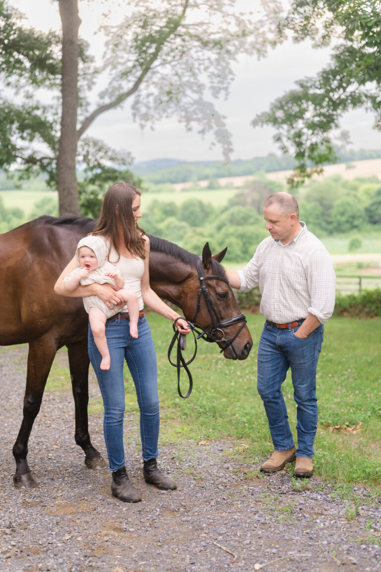 Mom, dad, and baby pose with their horse at the family farm.