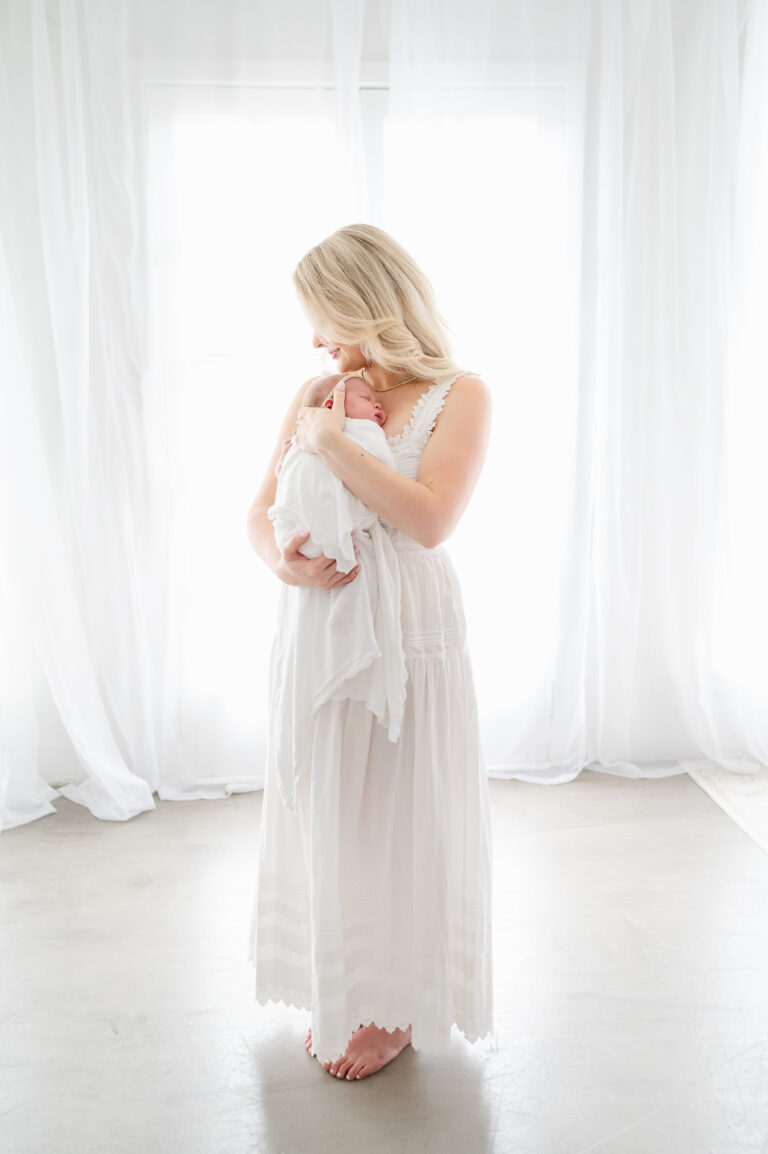 Mother holding her newborn baby during a light and airy newborn photography session in Virginia.