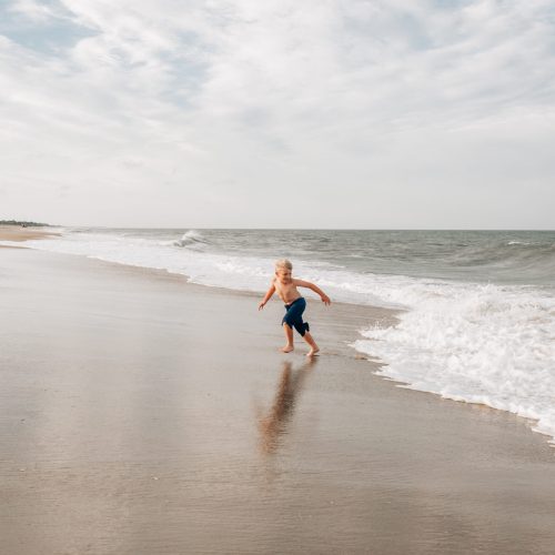 Boy running away from the waves at the beach